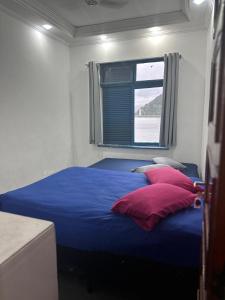 een slaapkamer met een blauw bed met rode kussens bij Pousada Recanto da Prainha in São Vicente