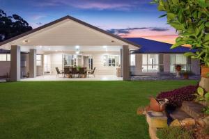 a house with a green lawn in front of it at Tarragal by Coast Hosting in Terrigal