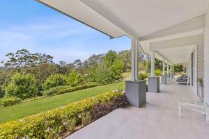 an exterior view of a house with a porch with a lawn at Tarragal by Coast Hosting in Terrigal +18 photos