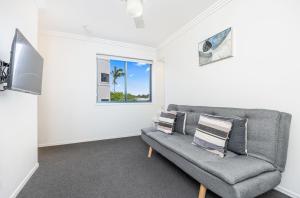 sala de estar con sofá gris y ventana en Grange Resort Hervey Bay, en Hervey Bay