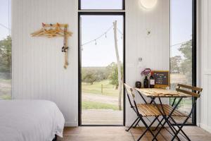 Un dormitorio con una cama y una mesa y una ventana. en Acre Away by Tiny Away, en Kangaroo Ground 13 fotos más