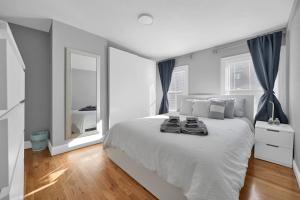 Un dormitorio blanco con una cama grande y un espejo. en Location+Comfort+Convenience, en Boston