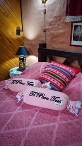Una cama rosa con dos almohadas encima. en Cabaña 'Te para Tres' Merlo San Luis, en Merlo