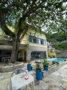 una casa con un albero e un tavolo di fronte di Pousada Recanto da Prainha a São Vicente