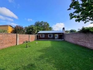 a backyard with a brick wall and a house at Cabaña zona vivero in Miramar +2 photos