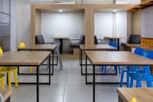 una clase con mesas de madera y sillas azules en Edificio Plaza U Wellness, en Pereira