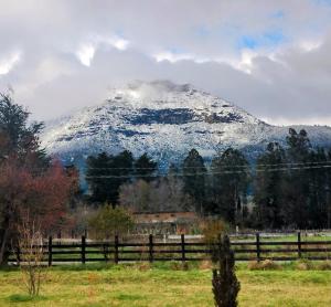 a snow covered mountain in a field with a fence at Brisas Volcanicas in Cunco