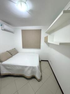 une chambre avec un lit dans une pièce blanche dans l'établissement Praia vila velha, à Vila Velha