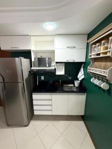 une cuisine avec des armoires blanches et un réfrigérateur dans l'établissement Praia vila velha, à Vila Velha