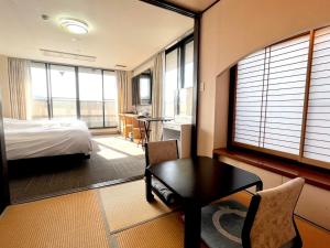ein Schlafzimmer mit einem Bett, einem Schreibtisch und einem Tisch in der Unterkunft サンシティーホテル山代 in Kaga