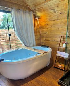 eine Badewanne in einem Zimmer mit einer Holzwand in der Unterkunft Cabana com banheira em formato de barril in Curitiba + 8 Fotos