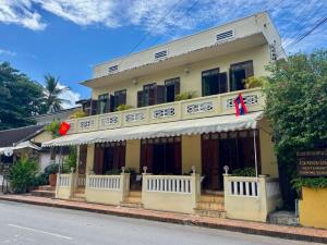ein gelbes Gebäude mit einer Flagge davor in der Unterkunft Baan Samsa in Luang Prabang
