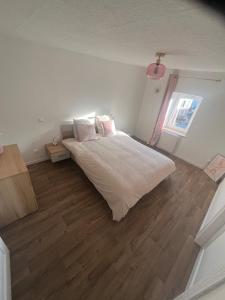una camera da letto con un letto bianco e un pavimento in legno di Spacieux appartement cozy a Saales
