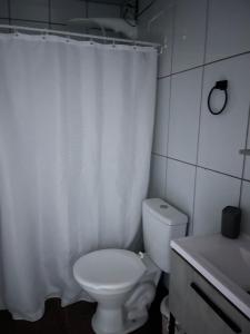 a bathroom with a toilet and a white shower curtain at Kit luxo com spa aquecido in Florianópolis +7 photos