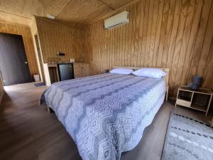 洛斯安赫莱斯Tiny House的带床和木墙的卧室