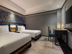 a hotel room with two beds and a desk and a tv at Hanoi Solis Hotel in Hanoi