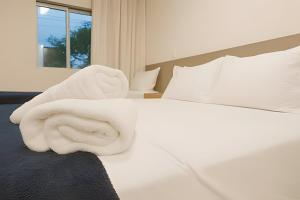 una camera da letto con un letto bianco con lenzuola e cuscini bianchi di Itaparica Beira-Mar [Confortável e Pé na areia] a Vila Velha