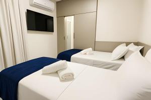 2 letti bianchi in una camera con TV di Itaparica Beira-Mar [Confortável e Pé na areia] a Vila Velha