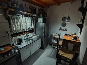 a kitchen with a refrigerator and a sink and a table at Luz Marina Cabaña Pettit Hidromasaje in Punta Colorada
