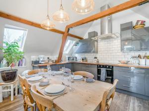 Una gran cocina con una mesa y sillas de madera. en Little Hewish Barn, en Milton Abbas