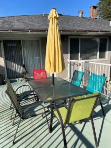 uma mesa com um guarda-sol amarelo e cadeiras em um deck em Charming Bright 3BR House - Upper Level Suite em Burnaby