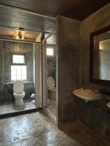 een badkamer met een toilet, een wastafel en een spiegel bij Sunnies 24 in Phra Ae beach