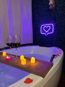 a bath tub with two glasses of wine and candles at Cabana com banheira em Curitiba in Curitiba