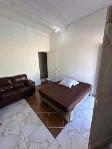 een slaapkamer met een bed en een bank in een kamer bij Pousada Ícone dos Mares in Mongaguá +5 foto's