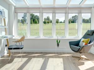 een woonkamer met ramen en een bank en stoelen bij Swallows Nest in Bibury