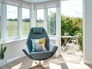 een blauwe stoel in een kamer met ramen bij Swallows Nest in Bibury