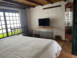 una camera da letto con un letto e una TV a schermo piatto di Hacienda La Armenia, Hotel Campestre BnB en Sopó a Sopo