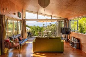 Una sala de estar con un sofá y un televisor. en Barefoot Spirit - Stay Waiheke, en Palm Beach