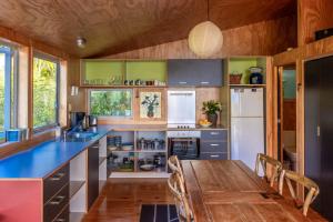 Una cocina con una mesa de madera y un refrigerador. en Barefoot Spirit - Stay Waiheke, en Palm Beach