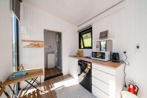 een kleine keuken met een aanrecht en een magnetron bij Stour Cabin by Tiny Away in Huiroa +24 foto's