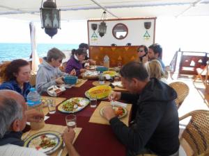 a group of people sitting at a table eating food at Dongolah Boat Abu Simbel in Tunqālah