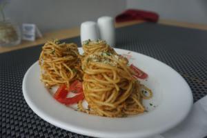 un plato de pasta con verduras en una mesa en Unisi Hotel Malioboro - Jogja Syariah en Yogyakarta