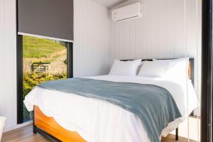 een slaapkamer met een groot bed en een raam bij Avon Cabin by Tiny Away in Huiroa