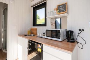 een keuken met een aanrecht met een magnetron en een wastafel bij Avon Cabin by Tiny Away in Huiroa