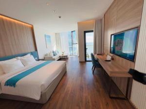 a bedroom with a large bed and a desk with a television at A LA CARTE Hạ Long Bay View biển tầng cao in Ha Long