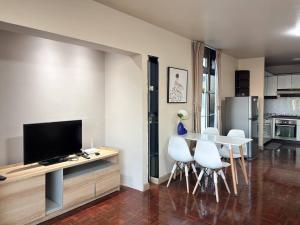 un soggiorno con TV e tavolo con sedie bianche di Bann-Kun Impact Muang Thong 2BR Condo Wi-Fi MRT Pink Near Airport DM 
