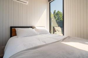 een slaapkamer met een wit bed en een groot raam bij Henge Cabin by Tiny Away in Huiroa