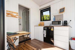 een kleine keuken met een koelkast en een tafel bij Henge Cabin by Tiny Away in Huiroa