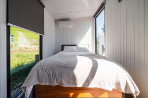 een slaapkamer met een bed en een groot raam bij Henge Cabin by Tiny Away in Huiroa