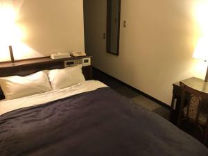 a bedroom with a bed with two lamps and a mirror at Hotel Welcome Matsumoto in Matsumoto