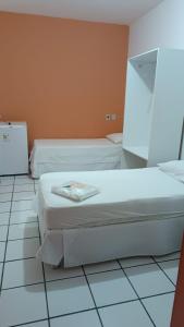 zwei Betten in einem Zimmer mit weißen Fliesenböden in der Unterkunft Pousada Terra do Sol in Caicó