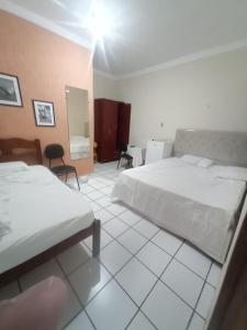 ein Hotelzimmer mit zwei Betten und einem Spiegel in der Unterkunft Pousada Terra do Sol in Caicó