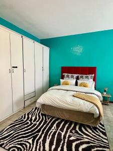 Ein Schlafzimmer mit einem Bett mit rotem Kopfteil und einem Zebrateppich in der Unterkunft Velvet Oasis Mbabane in Mbabane + 22 Fotos