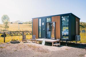 HuiroaStone Cabin by Tiny Away的一个小房子,有长凳和桌子