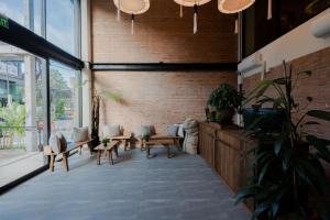 a room with benches and plants and a brick wall at The Tribe Nimman Boutique Hotel in Chiang Mai