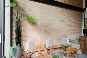 a brick wall with two wooden tables and pillows at The Tribe Nimman Boutique Hotel in Chiang Mai